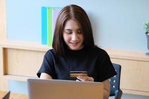 Young Woman holding credit card and using computer for online shopping photo