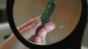 un technicien examine une micropuce à travers une grande loupe éclairée video