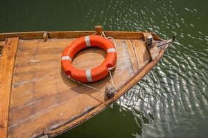 Boya salvavidas naranja en la proa de un pequeño bote de madera foto