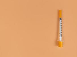 Jeringa de insulina sobre fondo naranja con espacio de copia foto