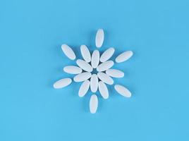 Forma de flor hecha de tabletas blancas sobre fondo azul.