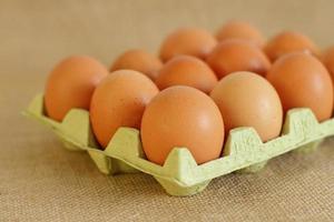 Tray of raw farm eggs on sackcloth background photo