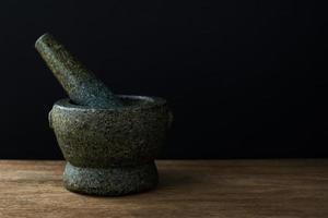 Stone Mortar on the wooden table and Black background with copy space photo