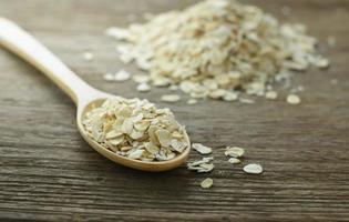 Oatmeal or Oat flakes in the Wooden Spoon on wooden table photo