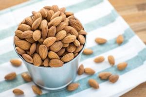 Almonds in stainless bucket on wooden table photo