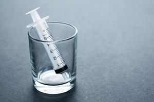 Empty syringe barrel in the small glass on the black background with copy space photo