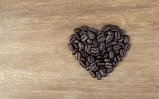 Granos de café en forma de corazón sobre fondo de madera foto