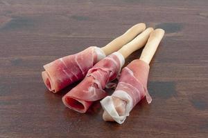 raw ham wrapped on breadstick photo