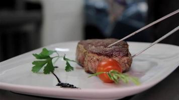 Steak wird auf einen dekorierten Teller gelegt video