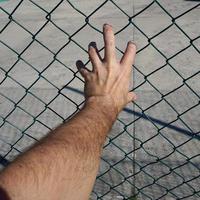 hand reaching a metallic fence photo