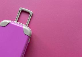 Pink plastic suitcase on pastel paper background Travel concept holiday summer adventure trip Flat lay with one simple thing Stock bright photo
