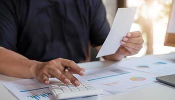 Un hombre que usa la calculadora para calcular facturas de gastos en su concepto de negocio en el lugar de trabajo foto