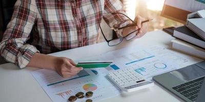 Joven mujer asiática comprobando facturas impuestos saldo de cuenta bancaria y calculando gastos de tarjeta de crédito concepto de gastos familiares foto