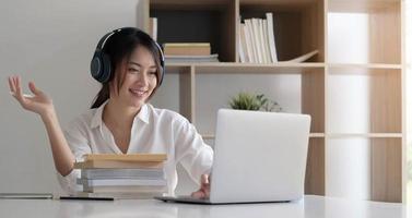 Vista lateral disparo a la cabeza sonriente dama de raza mixta con auriculares comunicándose con el cliente a través de una llamada de computadora por video foto