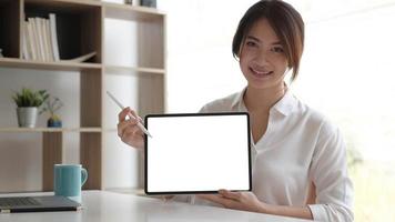 Close up view of female worker showing mock up tablet screen while standing in office room photo