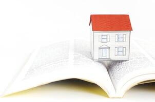 mortgage loans concept with paper house on textbooks photo