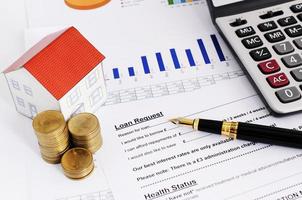 Home loans concept with close up fountain pen and loans request form and coins stack and paper house and calculate photo