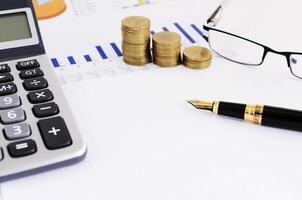 Business and Finance concept with close up of fountain pen and coins stack and eyeglasses  and calculator photo