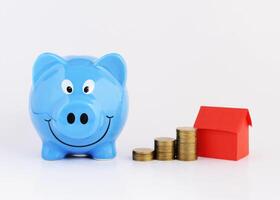 Blue piggy bank and coins stack and red paper house for money saving concept photo