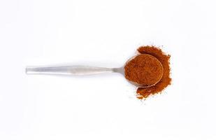 Red chili powder in metal spoon on white background photo