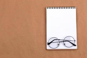 Flat lay top view of glasses and notepad on a beige background photo