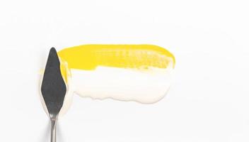 Una espátula de pintura aislada sobre un fondo blanco con amarillo foto
