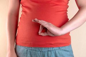 A close up view of the belly of a pregnant woman that holds her hands ok shape good health and good intestine excrete photo