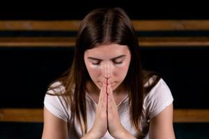 una niña cristiana con camisa blanca está orando con corazón humilde en la iglesia foto