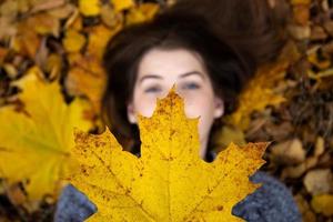 Top view of a cute girl with blue eyes holding a beautiful yellow maple leaf photo