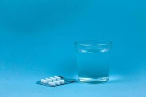 Glass Of Water And Pills On Blue Background with copy space for text photo