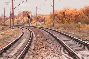 Perspective of railway track with fallen golden linden leaves on it photo