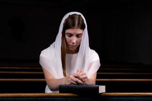 niña cristiana rezando con corazón humilde en la iglesia foto