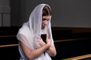 niña cristiana rezando con corazón humilde en la iglesia foto