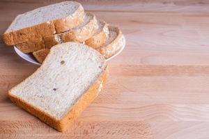 Slice whole wheat bread on wooden floor background photo