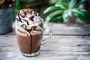Cacao chocolate caliente en taza de vidrio con crema batida foto
