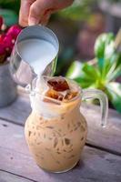 Pouring milk in a glass with latte coffee and iced photo