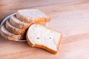 Slice whole wheat bread on wooden floor background photo