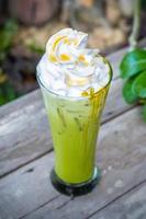 Ice matcha green tea with whipped cream on wooden table background photo
