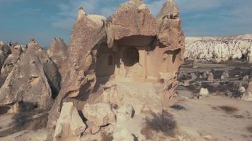 Pull-back, 4k aerial drone footage of the remains of a carved home in Cappadocia of central Turkey. The area is known for its distinctive fairy chimneys video