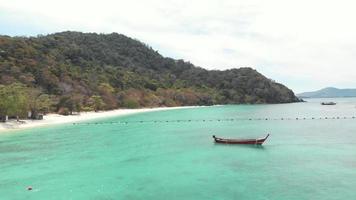 barco de pesca de cauda longa descansando sobre o mar raso turquesa cênico em banana beach em koh hey, ilha de coral, tailândia - foto aérea de baixo ângulo video