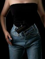 Asian woman with a pistol gun on her waist at the black background photo