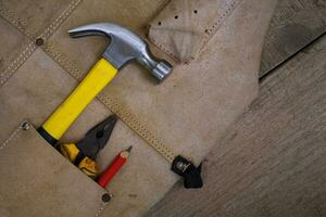 Colección de herramientas de mano antiguas para trabajar la madera en el delantal de cuero sobre un banco de trabajo de madera rugosa foto