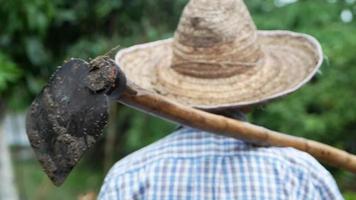 Vieux fermiers dans un chapeau de paille a tenu une houe sur son épaule et face au ciel en attendant le concept de l'agriculture rurale de la pluie video