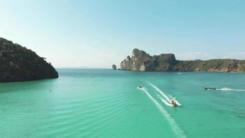 Pristine Loh Dalum Bay on a clear sunny day, crossed by motor boats in Ko Phi Phi Don Island Paradise in Thailand - Aerial Fly-over shot video