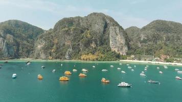 pittoresca vista panoramica della grande baia affollata di barche ormeggiate nel paradiso dell'isola di ko phi phi don in thailandia - ripresa panoramica aerea fly-over video