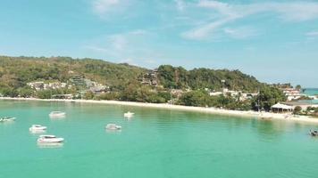 La paradisíaca bahía de la isla de Ko Phi Phi Don con barcos amarrados sobre cálidas aguas turquesas, Tailandia - Escaparate de sobrevuelo aéreo shot video