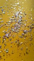 Foil pieces on yellow background with multi colored shine Abstract fashion stock macro photo