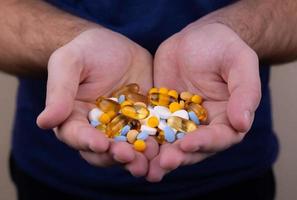 Un montón de pastillas multicolores en manos masculinas foto