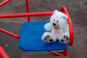 Close-up of one teddy bear sitting on a children's swing photo