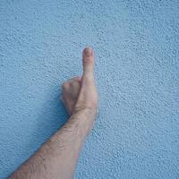 mano gesticulando en la pared azul foto